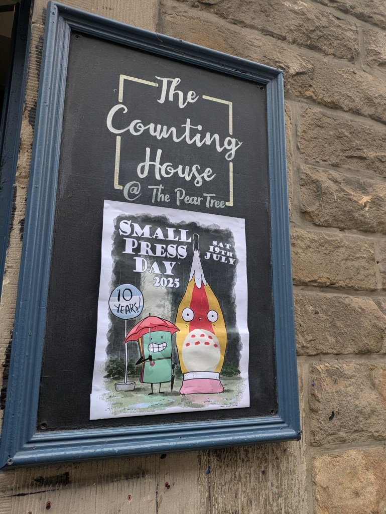 A poster for Small Press Day it features two creatures who look a bit like mushrooms.