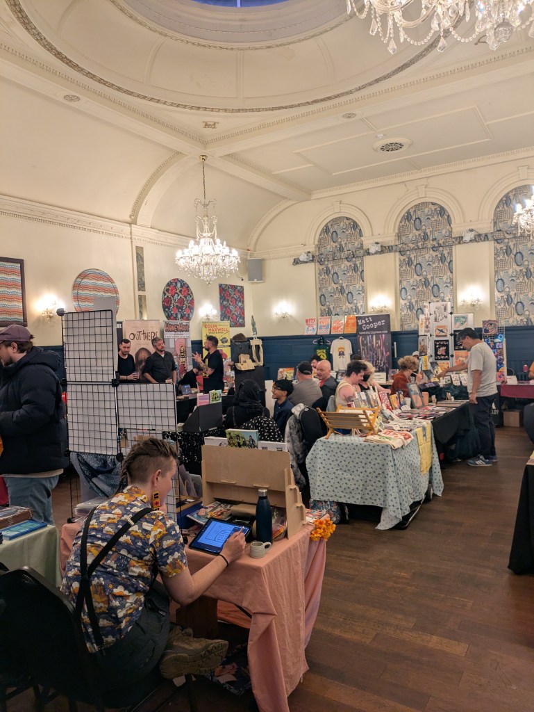 A room full of comic creators selling their books at tables