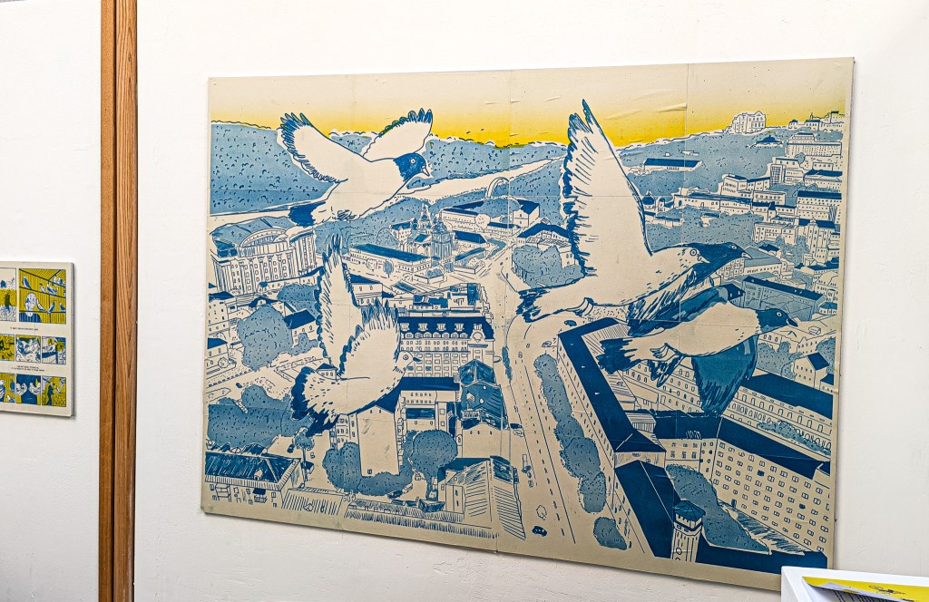 A large panel on the wall at a cafe. It shows pigeons in flight over a city.